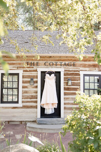 Wedding dress hangs from door of The Cottage and is beautifully framed by greenery