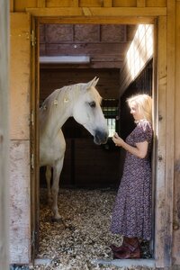 Leiko connecting with a horse inside a barn during an equine-guided healing session