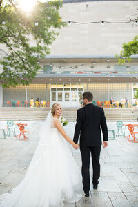 Bride and Groom walking away, holding hands at the Monona Terrace, Bride looks back smiling