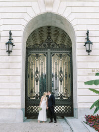 Bride and groom standing in front of ornate church doors for a timeless fine art wedding portrait by a Washington DC wedding photographer