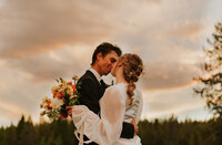 Shot from the waist up, a bride and groom about to kiss, shot slightly at an upwards angle from below their waist level.