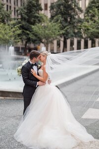 Bride smiles in camera as groom nuzzles her cheek