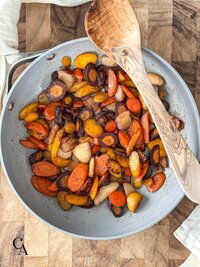A pan of sautéed carrots and a wooden spoon.