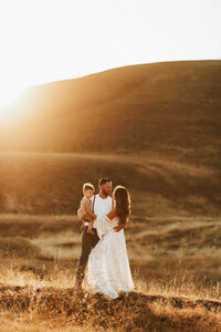 Bakersfield family in a golden field at sunset.
