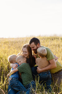 Parents hugging their children as they sit in a field