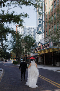 A photo of a bride and groom walking for a photo in the street