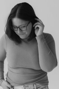 A person looking down as they pull their hair back behind one ear 