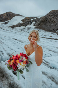 bride smiling with her bouquet at her Alaska glacier elopement