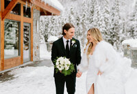 A bride and groom walk hand in hand on the patio at Greywolf Golf Course in Panorama British Columbia