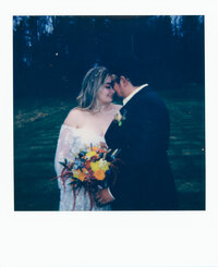 Polaroid photo of Dominique and Javi on their wedding day, standing forehead to forehead while holding a vibrant bouquet — captured on film as part of their own analog wedding film and Super 8 wedding storytelling journey.