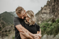 grand teton engagement pictures by jackson hole photographers  with man embracing woman as he stands behind her and they both smile
