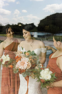 bride and bridesmaids standing in window smiling