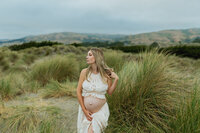 A pregnant mom holding her bare belly at the glamis sand dunes in California.