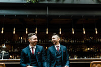 LGBTQ wedding couple laughing at the bar in Lot Six