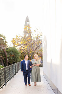 engaged couple walking in front of balboa park tower