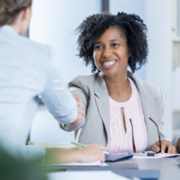 Woman shaking person's hand at table.