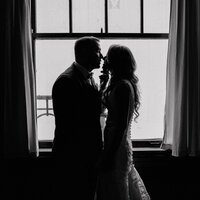 A bride and groom share a candid, nostalgic kiss in a black and white wedding photograph, capturing timeless romance and emotion in Spokane, Washington.