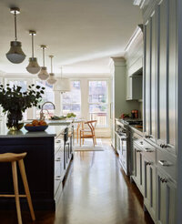 Interior Design Boston designed a traditional kitchen in a historic home with light grey cabinets, a navy blue island, and herringbone floors in a brownstone interior design project.