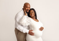 pregnant couple in white in studio by