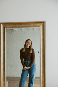 mirror portrait photo of girl with brown long sleeve shirt and jeans on