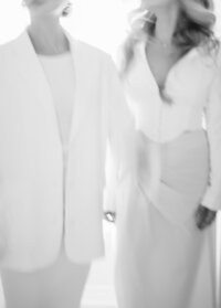 Minimalist cropped image of two artists in white attire, evoking modern elegance.