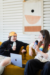 Two people sitting on a couch recording a podcast.