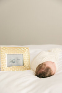 newborn lies next to a gold framed image of his embryo picture,  central Indiana family photographer