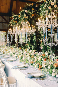 Table setting with floral centerpieces and large floral arrangements hanging from chandeliers