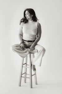  Black and white studio portrait of woman sitting on stool during lifestyle photography session in South Florida