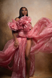 Black woman standing  wearing a pink tule gown showing  a leg