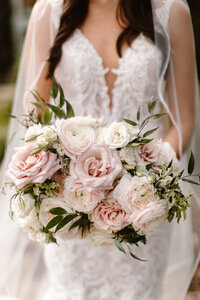 bride in deep 'v' dress holding pink and white floral bouquet