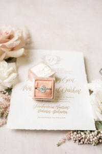 copper and white wedding invitations with soft pink ring box placed over the invitation
