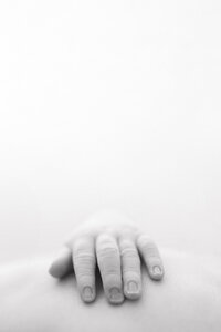 A black and white image of a newborn baby's hand laying on their tummy.