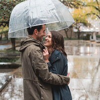 Couple snuggles under an umbrella on a rainy day at the Art Institute of Chicago South Gardens