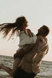 Husband picks up wife and twirls her at Siesta Key Beach, Florida.
