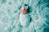 newborn posing on blue blanket for photography session