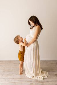 Expectant mom in an orange dress with her son in a garden