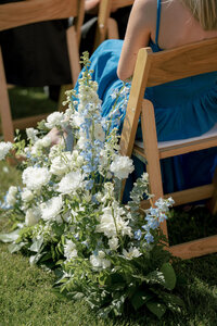 Soft blue and white floral arrangements lining the aisle at a luxury outdoor Jackson, Wyoming wedding.