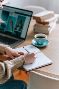 woman writing in journal with cup of coffee  on desk