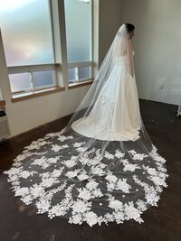 bride trying on her custom lace veil with her wedding gown