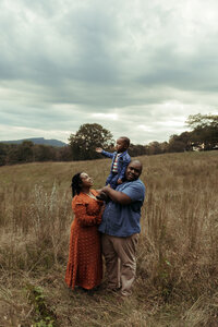 Family Photographer, mom and dad each holding up one child into the air having fun together