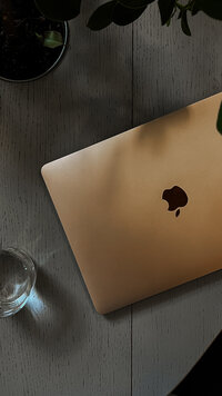 A closed rose gold laptop on a table