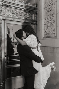 A couple kissing while the man lifts up his fiancé