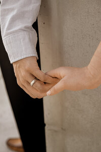 Couple holding hands during engagement session against glowing sun in the Northern Sedona. 
