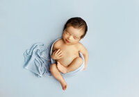 Airy newborn photograph with gentle highlights, minimal styling, and soft neutrals for a modern fine-art look.