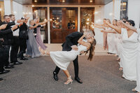 A couple doing the dip as they walk through family and friends on their way to their reception