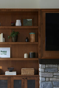 Girl with brown hair, sitting at a kitchen island with green kitchen cabinets behind her, flipping through a large cookbook