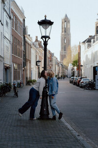 Twee verliefde meiden geven elkaar een kus in het centrum van Utrecht met de dom op de achtergrond
