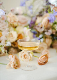 glass of champagne against reception wedding flowers