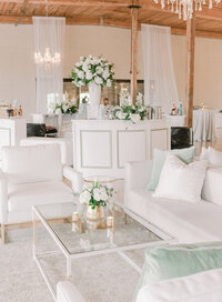 wedding reception with white table and chairs with floral three arrangements